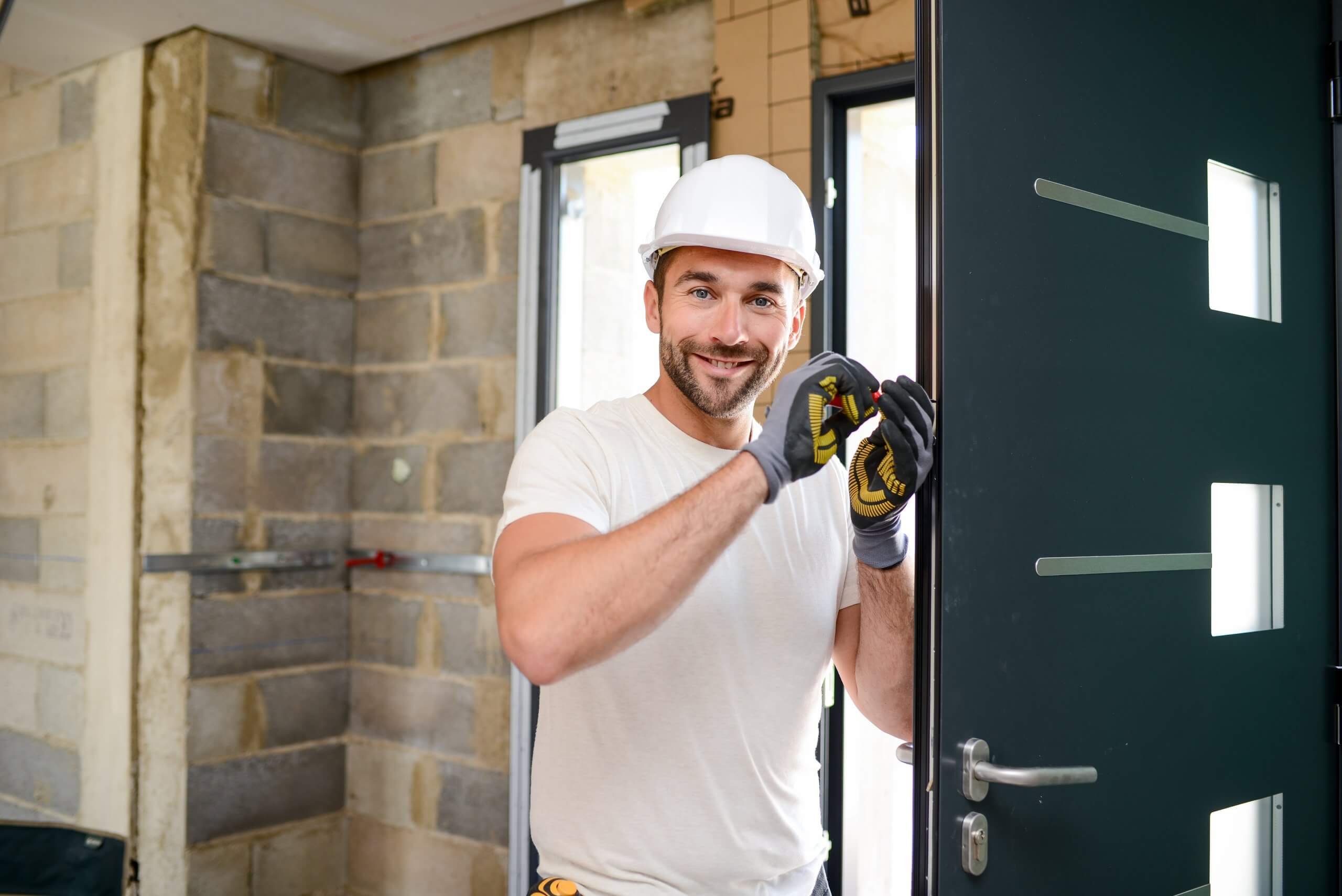 handsome young man installing door in a new house construction site